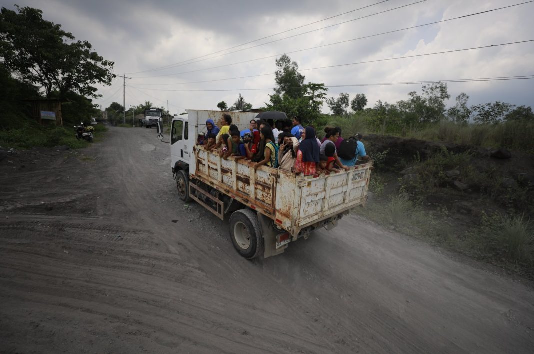 Penduduk desa Filipina yang tinggal di kaki gunung berapi Mayon mengendarai truk selama evakuasi massal di kota Guinobatan, provinsi Albay, Filipina, 9 Juni 2023. (Foto EPA)