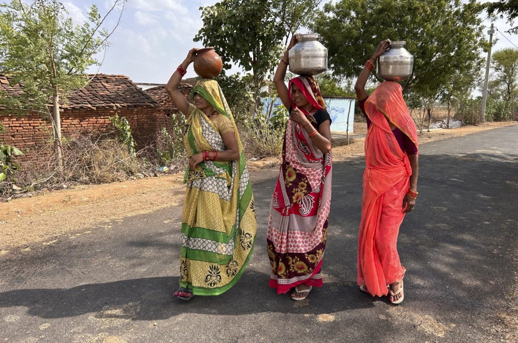 Wanita berjalan sambil membawa kendi berisi air minum pada sore musim panas di Lalitpur, negara bagian Uttar Pradesh, India, Sabtu, 17 Juni 2023. (Foto AP)