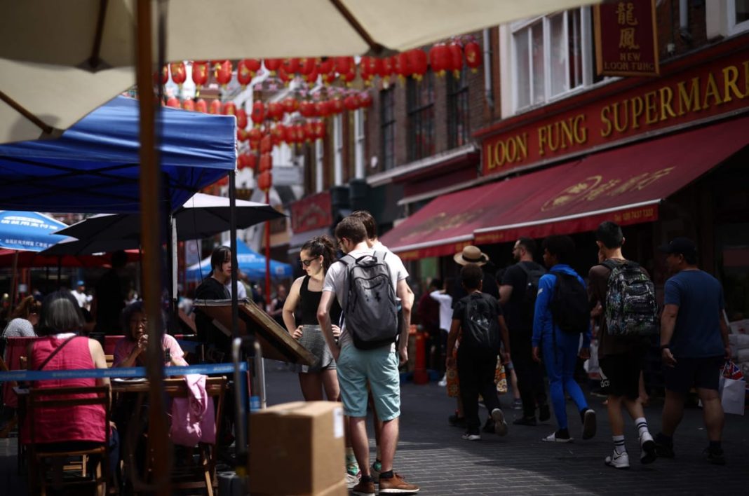 Anggota masyarakat membaca menu di luar sebuah restoran di kawasan Chinatown Soho di London, Inggris, 18 Juni 2023. (Foto: AFP)