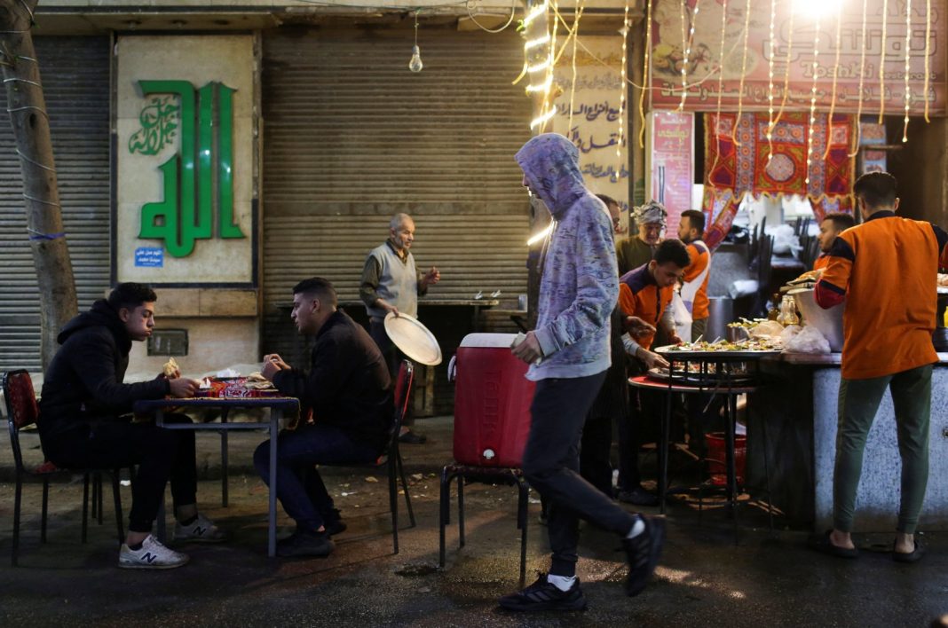 Orang-orang duduk di restoran jalanan untuk makan makanan tradisional Mesir 