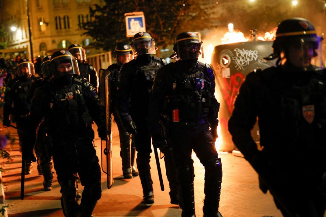 Sekelompok petugas polisi berjalan saat orang-orang melakukan protes setelah kematian Nahel, seorang remaja berusia 17 tahun yang dibunuh oleh seorang petugas polisi Prancis di Nanterre saat berhenti lalu lintas, dan menentang kekerasan polisi, di Paris, Prancis, 30 Juni 2023. (Foto: Reuters)
