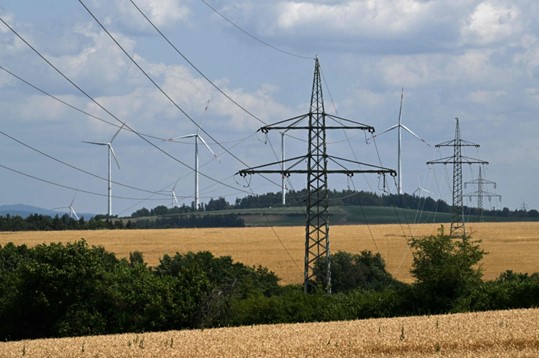 Turbin angin berdiri di latar belakang tiang listrik di dekat desa Bavaria di Schnabelwaid, Jerman selatan, 17 Juli 2023. (Foto: AFP)