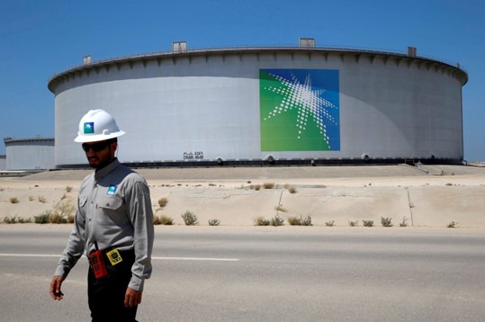 Seorang karyawan Aramco berjalan di dekat tangki minyak di kilang minyak dan terminal minyak Ras Tanura Saudi Aramco di Arab Saudi, 21 Mei 2018. (Foto: Reuters)